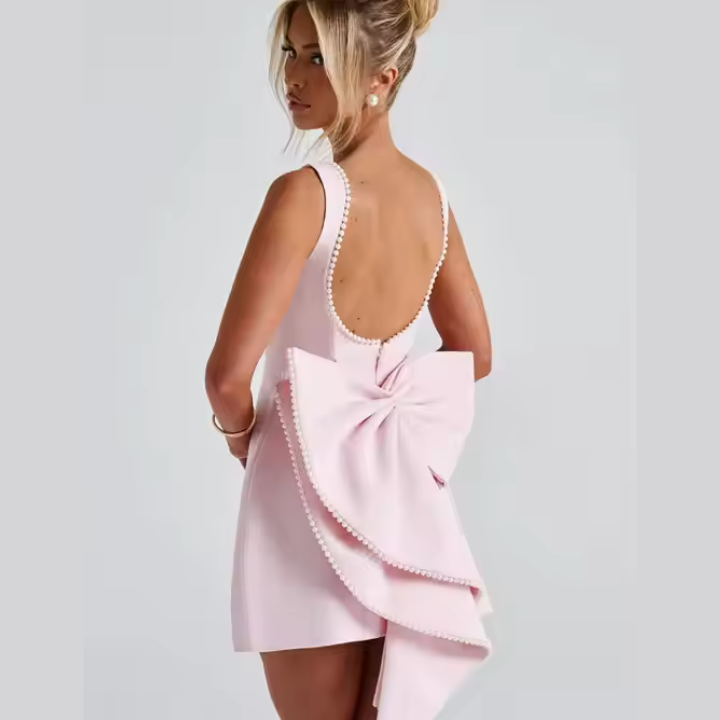 Model wearing Celestine backless mini dress with pearl bow detail – ODI-ONE FASHION
