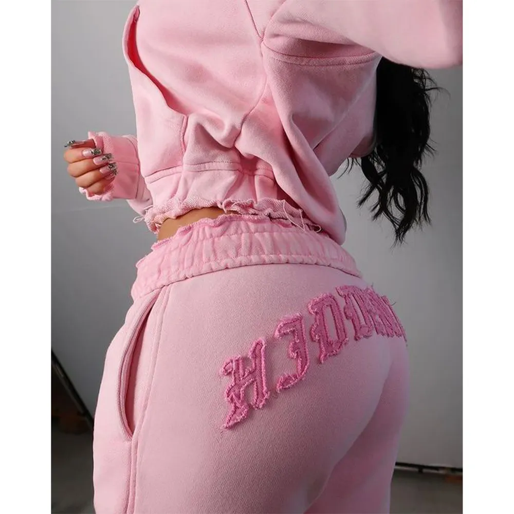 Person wearing pink sweatpants with 'HEIDI' embroidery on a plain background