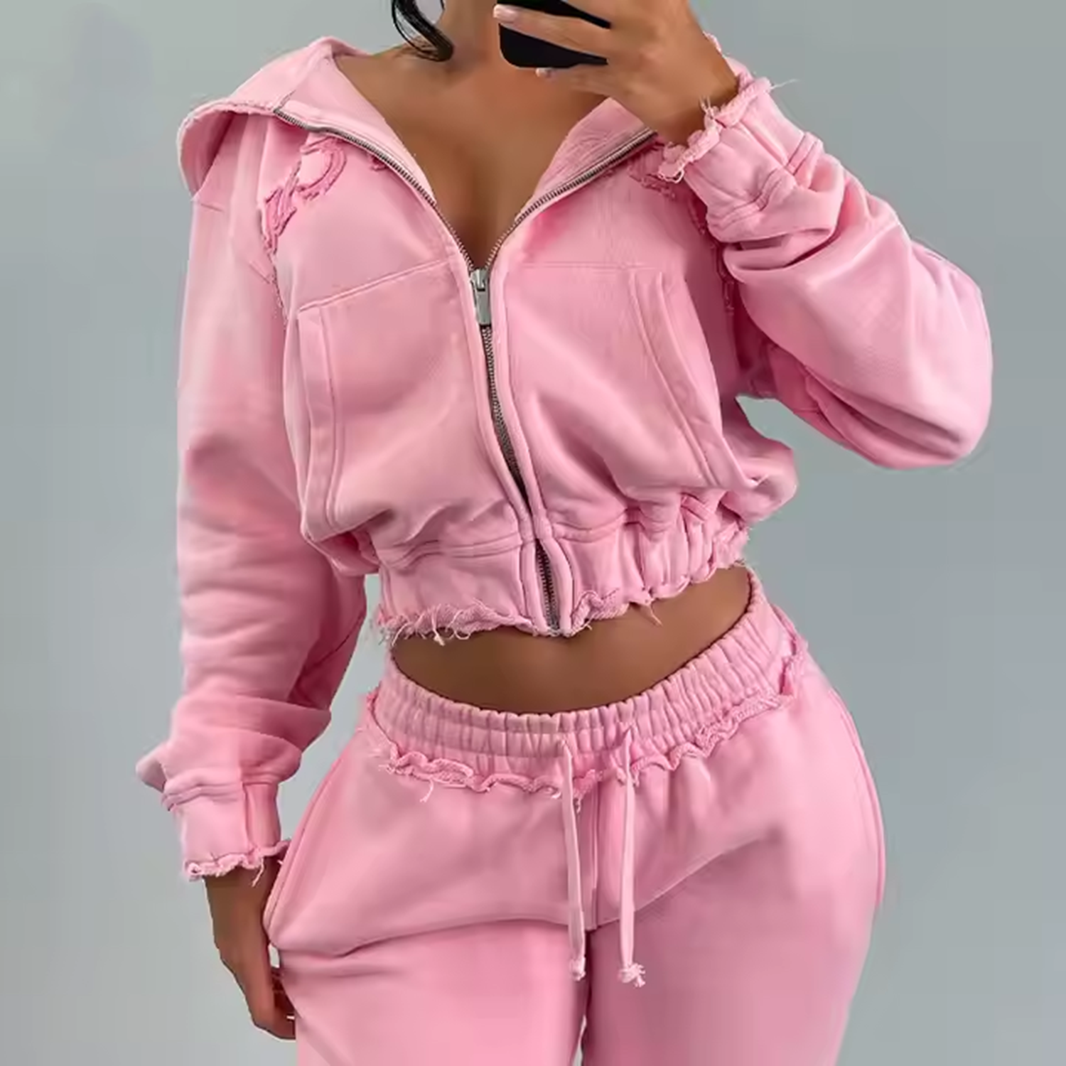Person wearing a pink tracksuit against a gray background