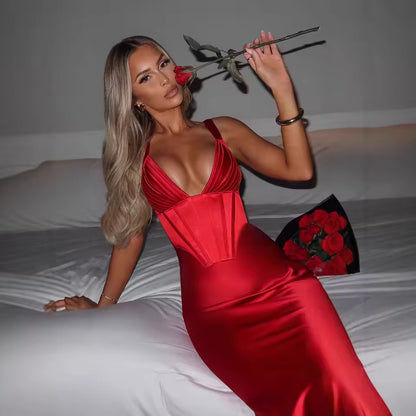 Woman in a red dress holding a red rose on a bed