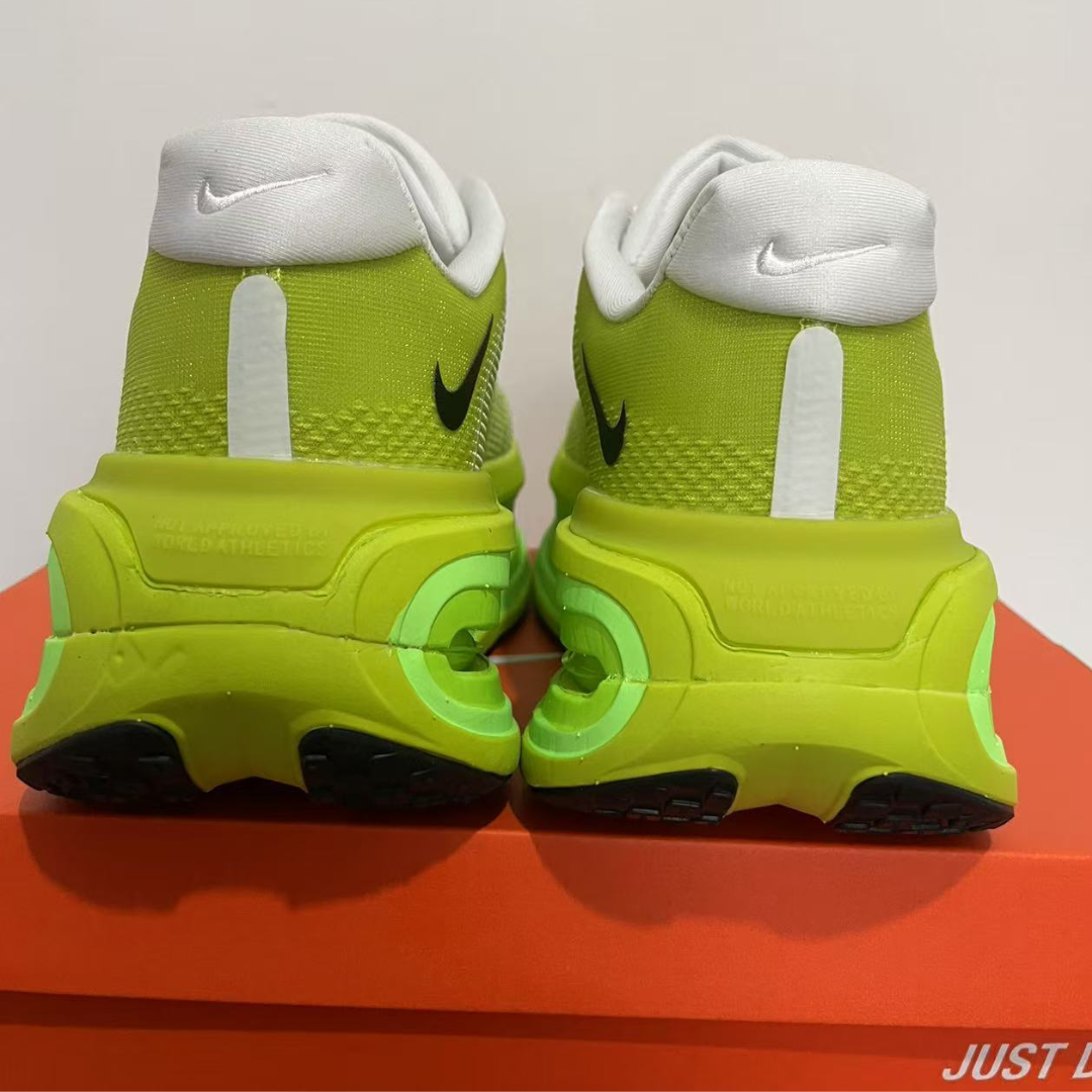 Pair of neon green sneakers with white and black accents on a red and gray background