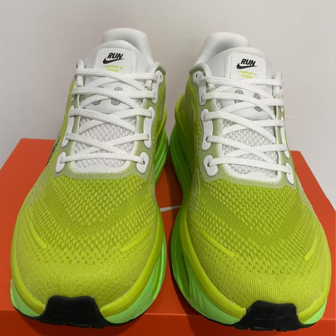 Pair of bright green running shoes with white laces on a red surface.
