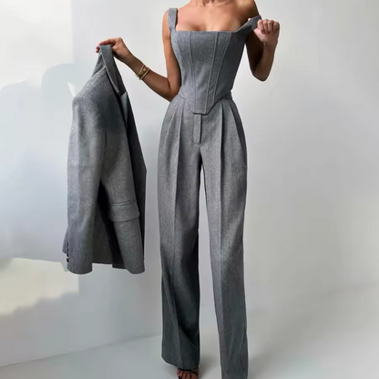 Person wearing a gray jumpsuit holding a matching jacket against a white background
